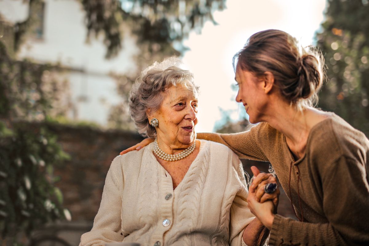 A support worker walking outdoors with an older individual, smiling together
