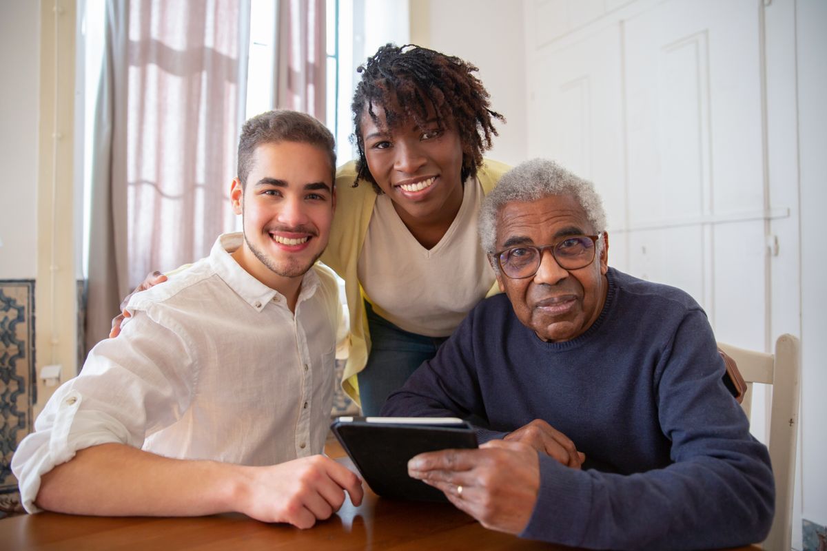 A support worker with two individuals smiling together at home